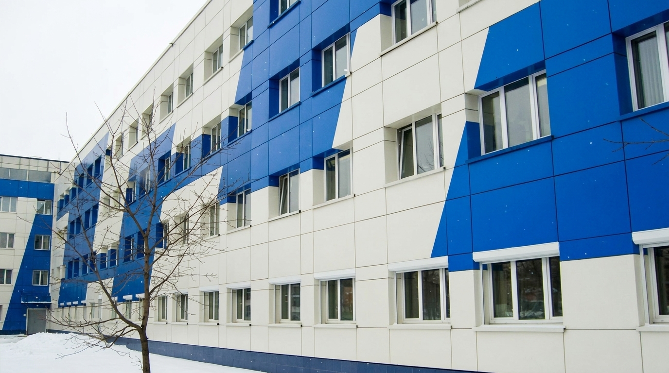 Біло-синій фасад сучасної будівлі Сучасний багатоповерховий фасад будівлі з біло-синім облицюванням і рядами вікон узимку