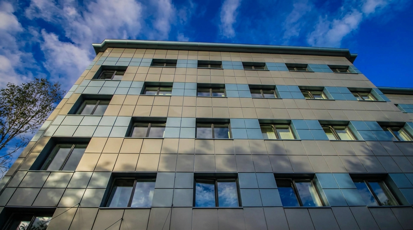 Сучасний фасад багатоповерхової будівлі Сучасна багатоповерхова будівля з вентильованим фасадом і великими вікнами на тлі блакитного неба з хмарами