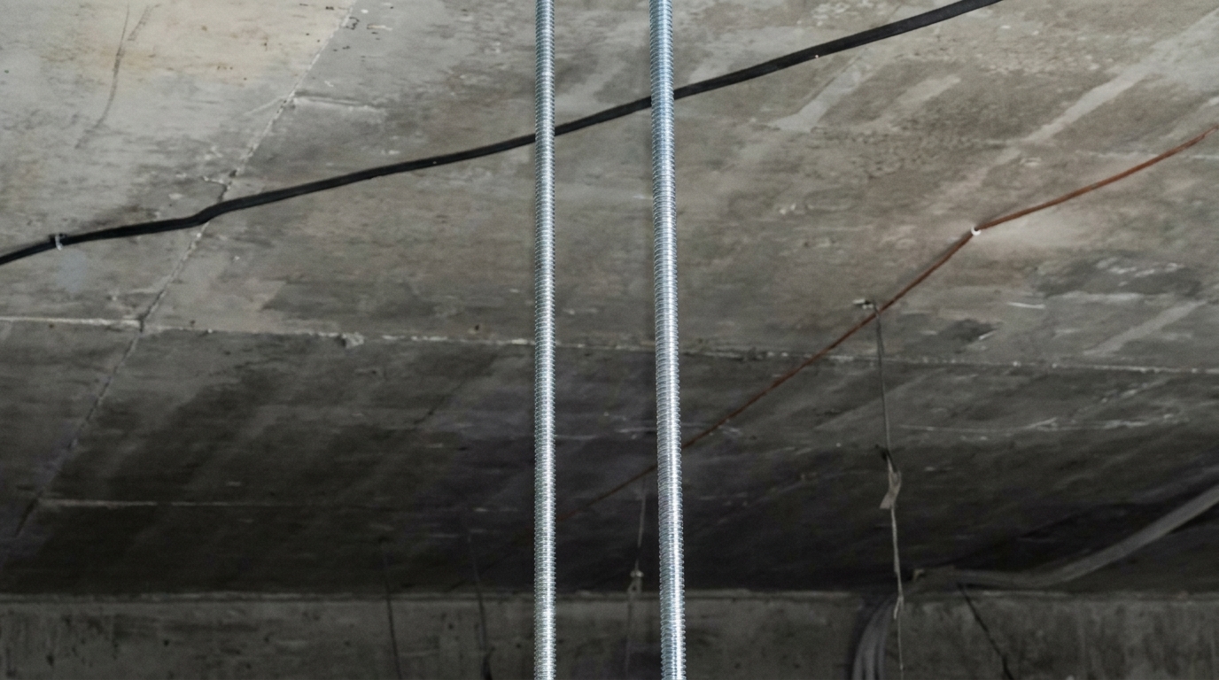 Монтажні елементи на бетонній стелі Бетонна стеля в приміщенні з підвісними різьбовими шпильками та прокладеними кабелями